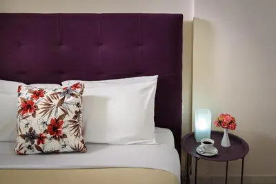 a bed with a purple headboard and a table with a candle at Room 25 in Chania Town