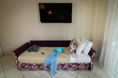 a couch with a blue scarf on it with a television on the wall at Room 25 in Chania Town