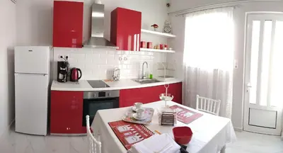 a kitchen with red cabinets and a table and a white refrigerator at Sunday Apartment Chania 2B in Chania Town