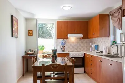 a kitchen with wooden cabinets and a table with chairs at Kaktos 1 in Kissamos