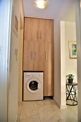 a laundry room with a washing machine and wooden cabinets at Emerald Apartment Halepa in Chania Town