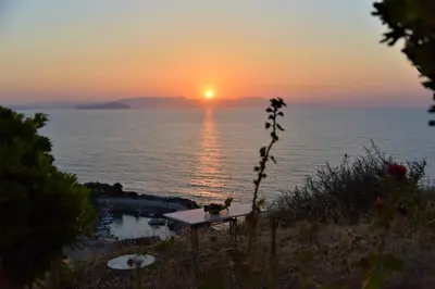 a sunset over the ocean with a table with a cat on it at Emerald Apartment Halepa in Chania Town