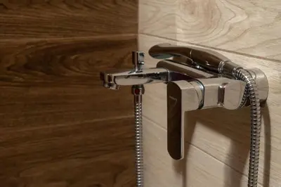 a shower faucet in a bathroom with wooden floors at Abella Hotel in Agia Marina Nea Kydonias