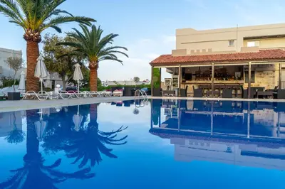 a pool at a resort with palm trees and a bar at Abella Hotel in Agia Marina Nea Kydonias