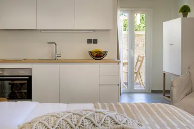 a kitchen with white cabinets and a bed in a room at s u e ñ o - studios and apartments, with shared pool in Kato Daratso