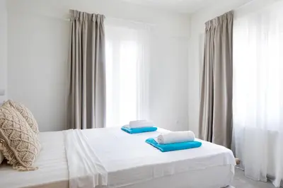 a bedroom with a bed with two blue pillows on it at s u e ñ o - studios and apartments, with shared pool in Kato Daratso