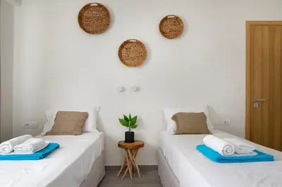 two beds in a room with white walls at s u e ñ o - studios and apartments, with shared pool in Kato Daratso