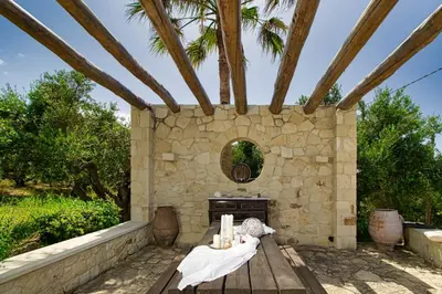 a stone fireplace in a patio with a wooden table at Venizelos Studios in Plataniás