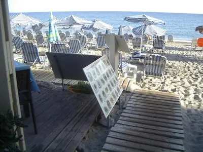 a wooden deck with chairs and umbrellas on the beach at Despina Apartments in Plataniás