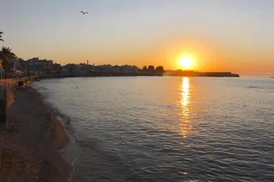 a sunset on a beach with the sun reflecting in the water at Casa Dei Miracoli in Chania Town