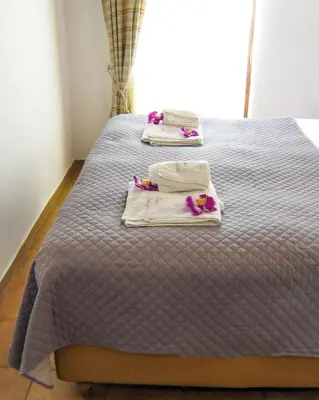 two towels on a bed with purple sheets and purple flowers at Casa Dasyra in Chania Town