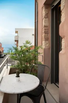 a table and chairs on a balcony with a table and a window at Chania Escapes City Loft 50 meters by the Sea in Chania Town