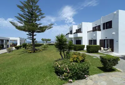 a large white building with a palm tree in a yard at Geraniotis Hotel and Resort in Plataniás