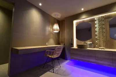a bathroom with a vanity with a chair and a mirror at Geraniotis Hotel and Resort in Plataniás