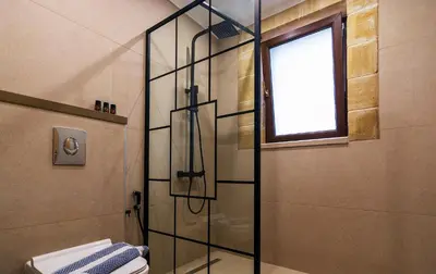 a bathroom with a shower with a toilet and a window at Anma Villa in Palaiochóra