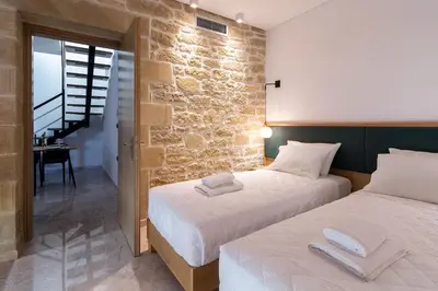 two beds in a room with a stone wall at Anma Villa in Palaiochóra