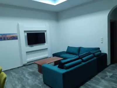 a living room with a blue couch and a tv at Utsi in Liyidhés