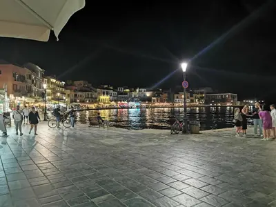 a group of people walking on a pier at night at Porto Chania in Chania Town