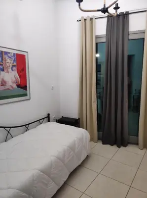 a bedroom with a bed and a window with curtains at Porto Chania in Chania Town