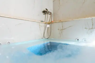 a bath tub filled with blue water next to a shower at Konmari Boutique Suites in Chania Town