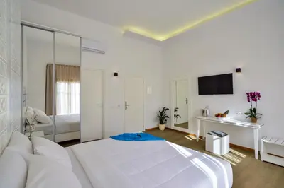 a white bedroom with a large bed and a mirror at Elia Portou Luxury Residence in Chania Town