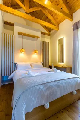 a large white bed in a room with wooden ceilings at Villa Skyphos in Ammoudari