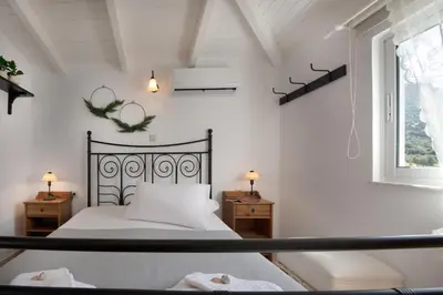 a white bedroom with a bed and a window at Dream House Efi in Ravdhoúkha