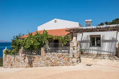 a house with a stone wall next to the water at House with Private Place To Swim, Solitary, View in Ravdhoúkha