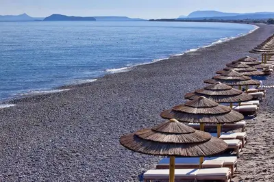 a row of beach umbrellas on a rocky beach at House with Private Place To Swim, Solitary, View in Ravdhoúkha