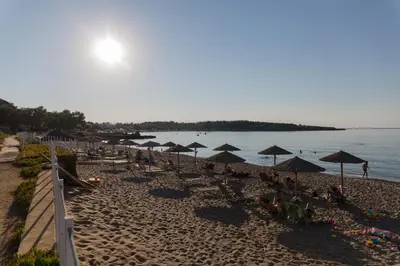 a beach with umbrellas and people sitting on the sand at Irene Suite Chania in Kato Daratso