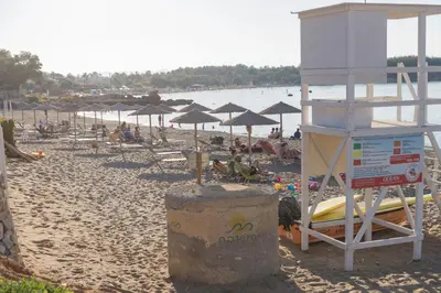 a beach with umbrellas and people sitting on the sand at Irene Suite Chania in Kato Daratso