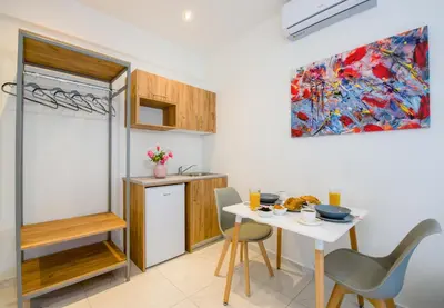a kitchen with a white table and chairs and a painting at Linda Apartments Platanias in Plataniás