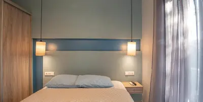 a bedroom with a bed with two lights above it at On the sand 1 in Palaiochóra