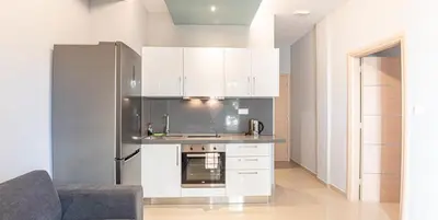 a kitchen with white cabinets and a stainless steel refrigerator at On the sand 2 in Palaiochóra