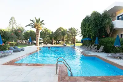a swimming pool with chairs and umbrellas in a resort at On the sand 2 in Palaiochóra