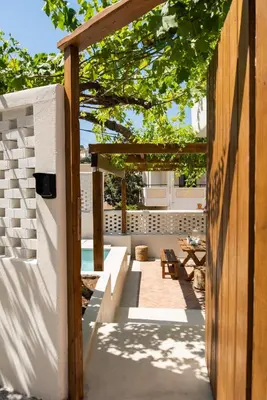 a patio with a wooden pergola and a table at Cretan Soul in Plataniás
