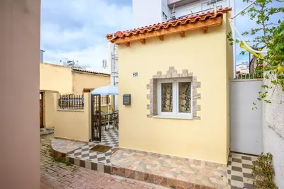 a small yellow house with a window and a courtyard at Matzi House in Chania Town