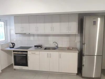 a kitchen with white cabinets and a stainless steel refrigerator at Alexia Rooms in Palaiochóra