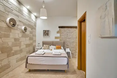 a bedroom with a bed and a brick wall at Semeli Apartment in Kissamos