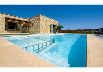 a swimming pool with blue water in front of a house at Villa Arietta in Kharkhalianá