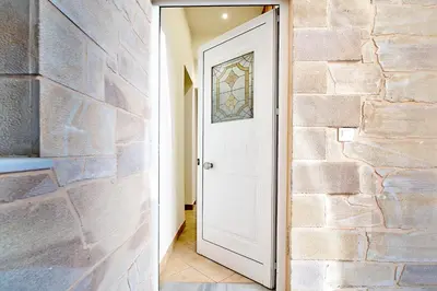 a hallway with a white door and a stone wall at Ekavi Apartment in Kissamos