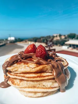 a stack of pancakes with strawberries on a plate at Elafonisi Rooms For Rent in Elafonisi