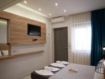 a hotel room with two beds and a flat screen tv at Erotokritos Studios near the beach in Agia Marina Nea Kydonias