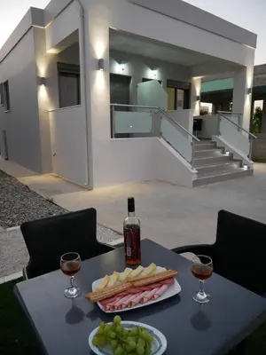 a table with a plate of food and two glasses of wine at Erotokritos Studios near the beach in Agia Marina Nea Kydonias