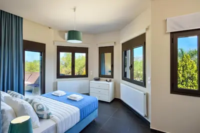 a bedroom with a bed and two windows at Villa Abelizia in Chania Town
