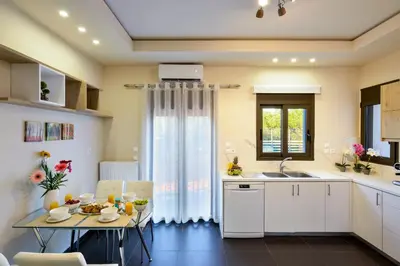 a kitchen with white cabinets and a table and a window at Villa Abelizia in Chania Town