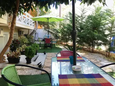 a patio with a table and chairs and an umbrella at The Green Apartment, 1 min walk from Kalamaki beach in Kalamaki Chanion
