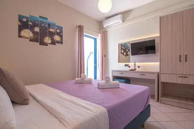 a bedroom with a large bed with a purple blanket at Libyan Sunrise in Palaiochóra