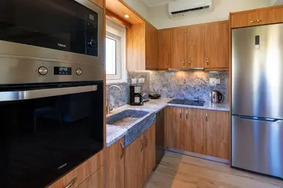 a kitchen with wooden cabinets and a stainless steel refrigerator at Bitsakis Family II - Paleochora Luxury House in Palaiochóra