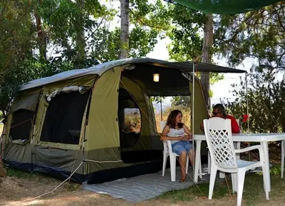 a man and woman sitting at a table in front of a tent at Camping Mithimna in Kissamos